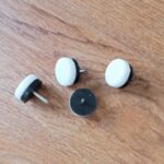 furniture studs made of metal and plastic, arranged on a wooden surface for cabinet and chair assembly