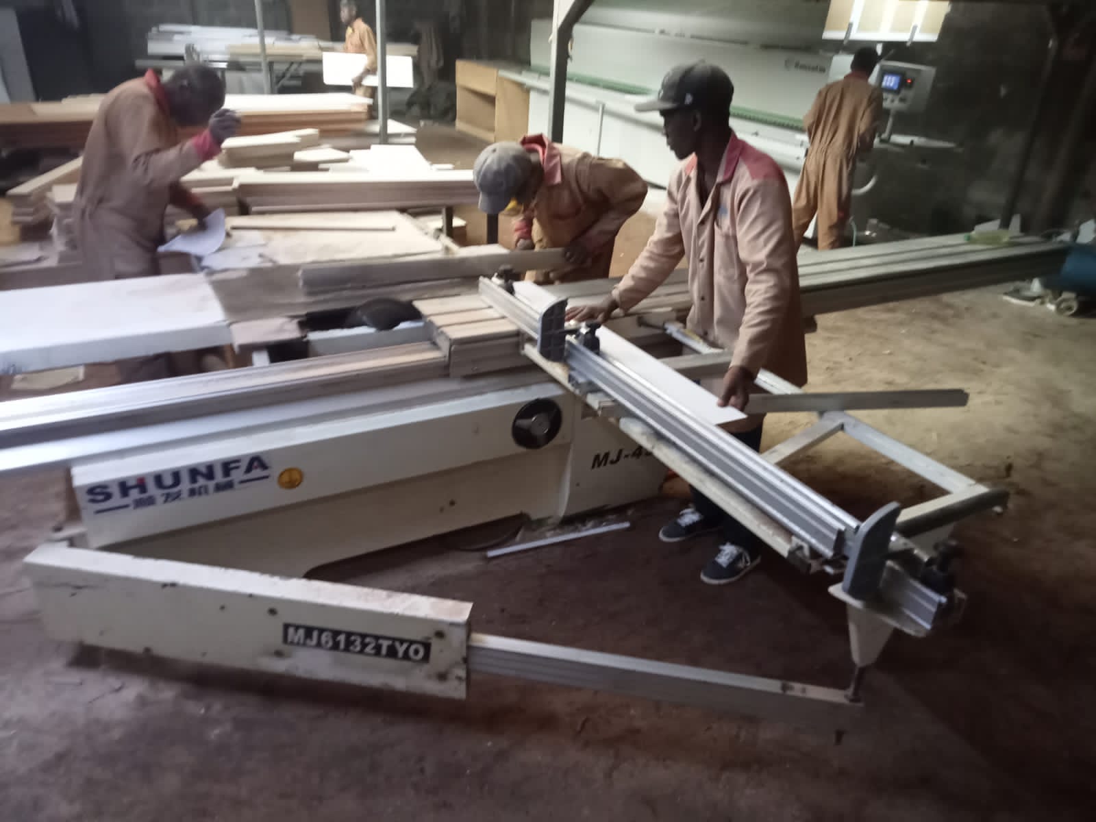 Technician performing precision board cutting in a woodworking workshop in Kenya